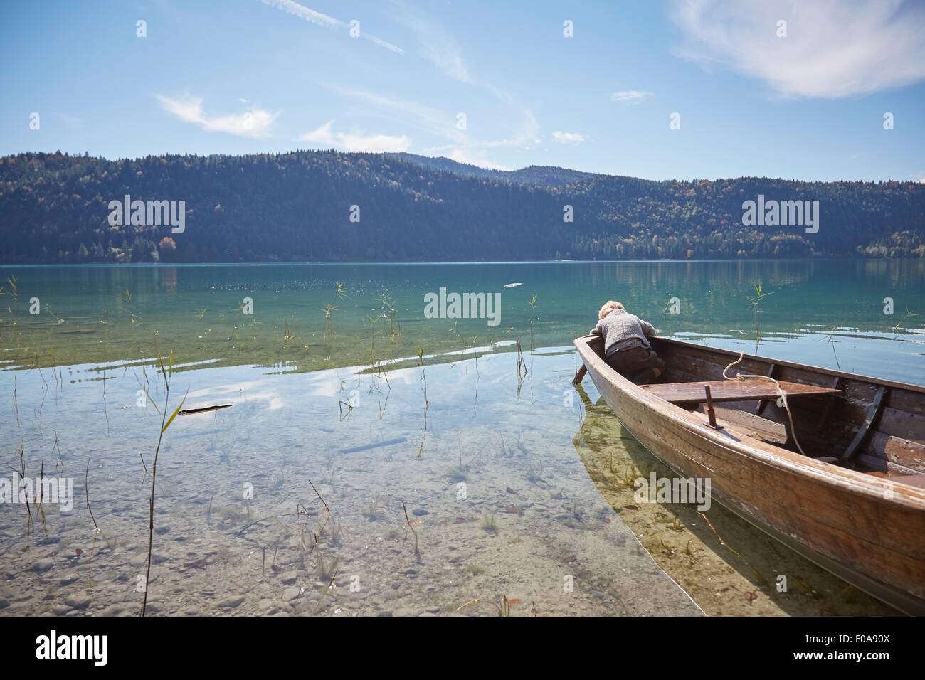 La flexion de l'avant du garçon bateau à rames et à la recherche dans le lac, Kochel, Bavière, Allemagne Banque D'Images