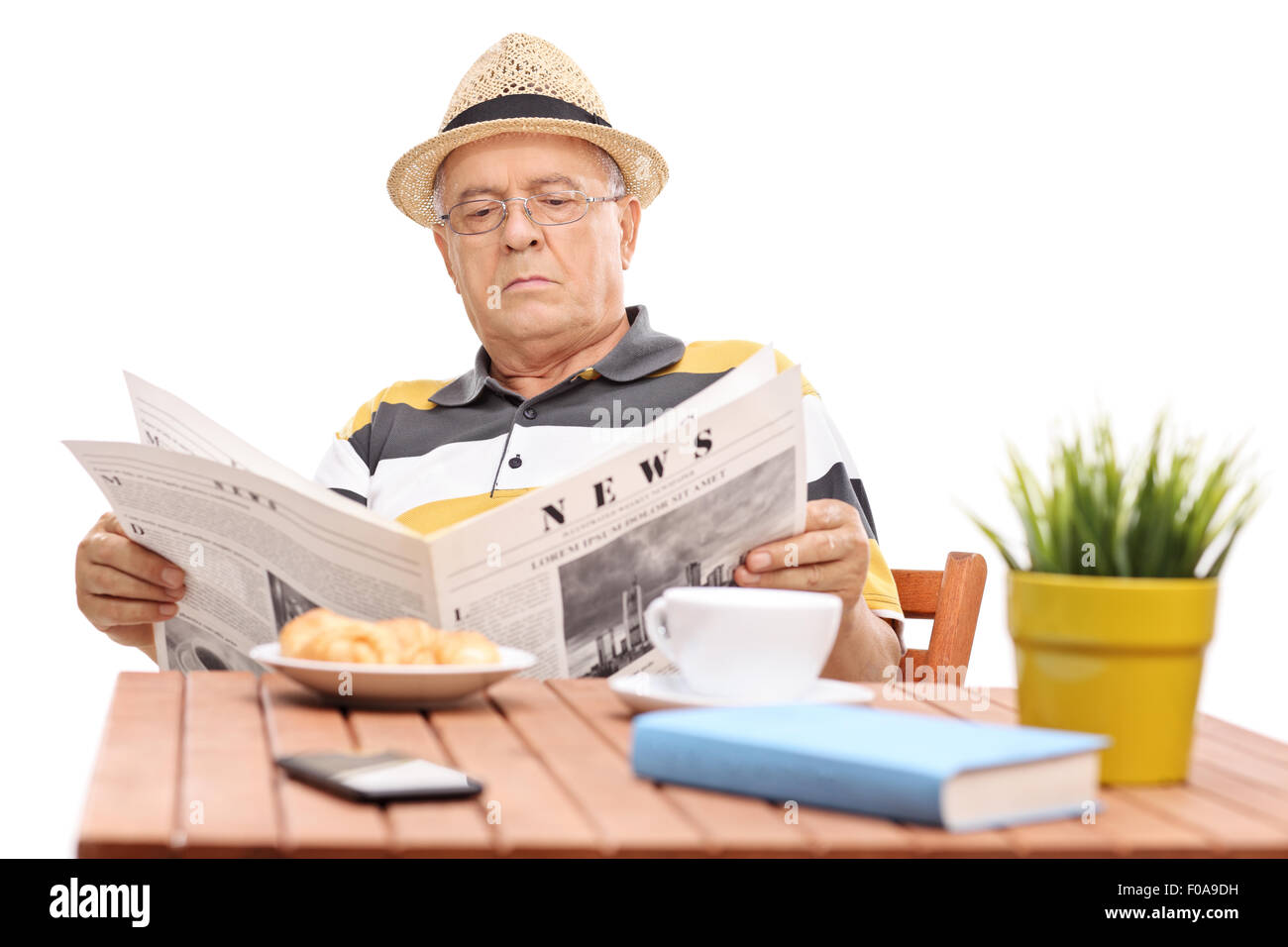 Homme mature lire un journal assis à une table de café avec quelques croissants sur il isolé sur fond blanc Banque D'Images