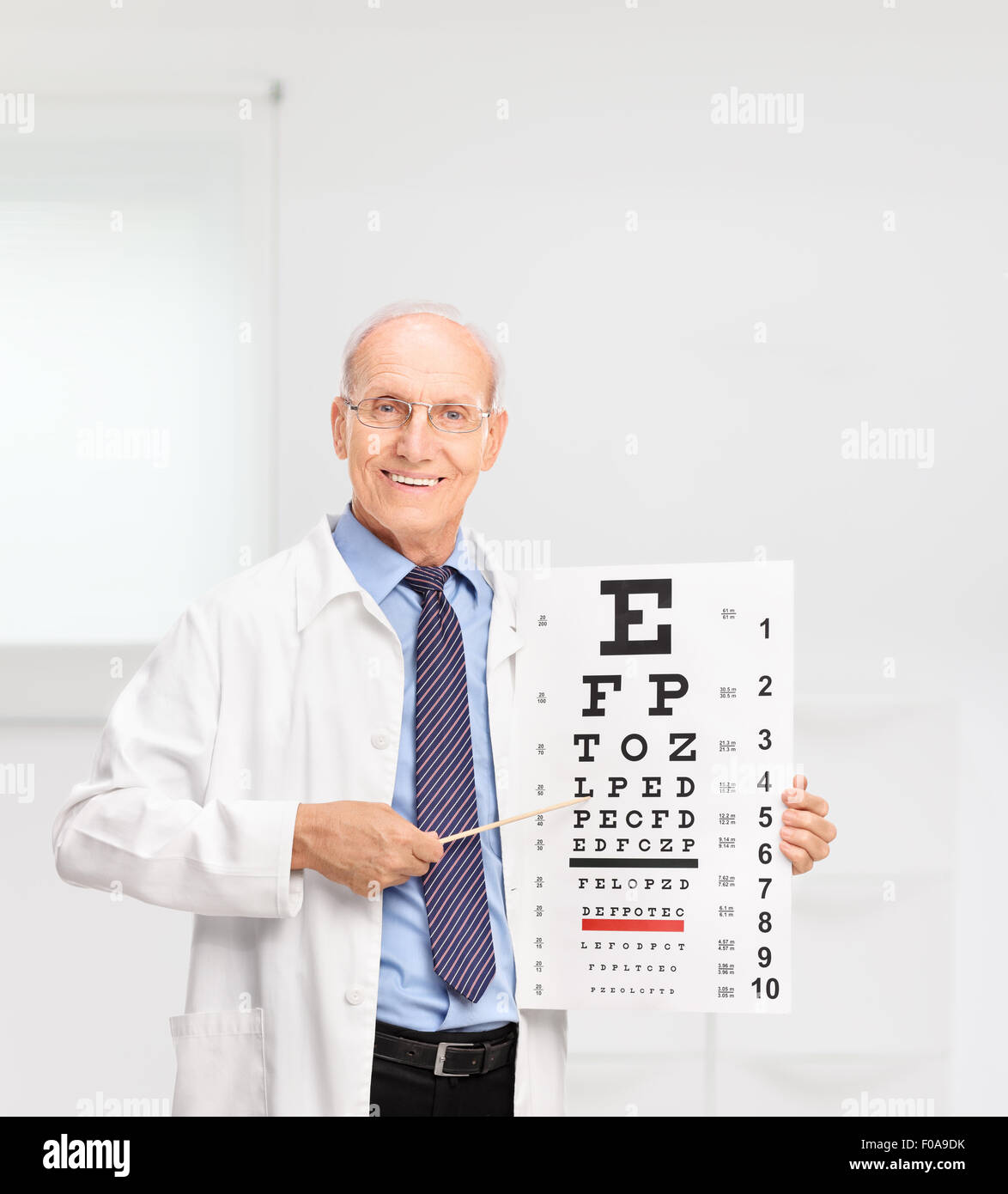 Opticien à maturité la tenue d'un tableau et en pointant sur elle avec un bâton en bois dans un hôpital Banque D'Images
