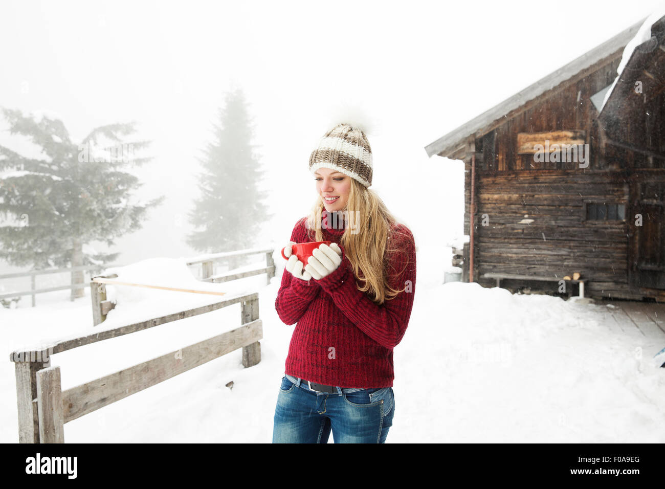 Young woman drinking coffee in snow hors cabine Banque D'Images