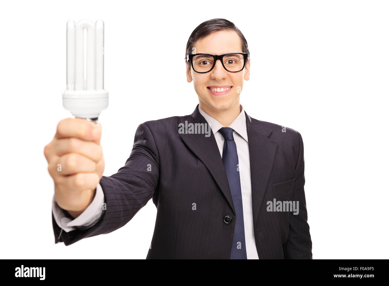 Young businessman holding une ampoule à économie d'énergie et regardant la caméra isolé sur fond blanc Banque D'Images