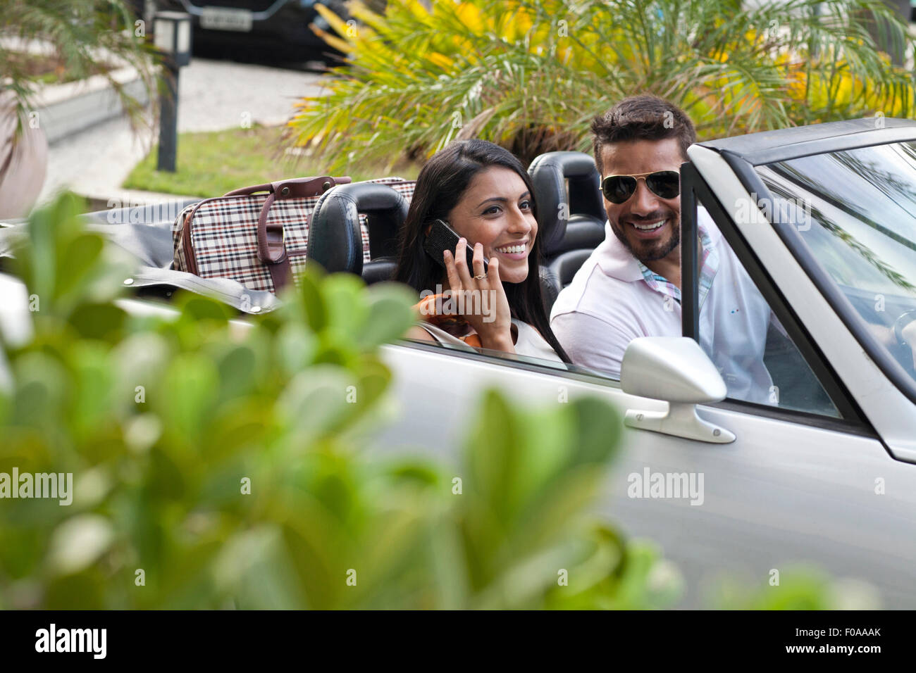 Couple en voiture décapotable, woman using smartphone Banque D'Images