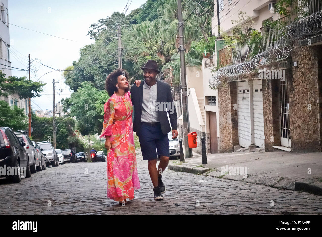 Couple walking down rue pavée, smiling Banque D'Images