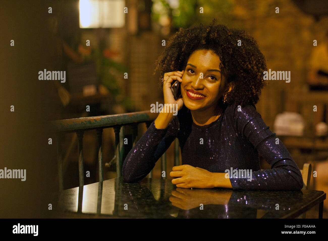 Young woman sitting at table at bar, à l'aide de mobile phone Banque D'Images