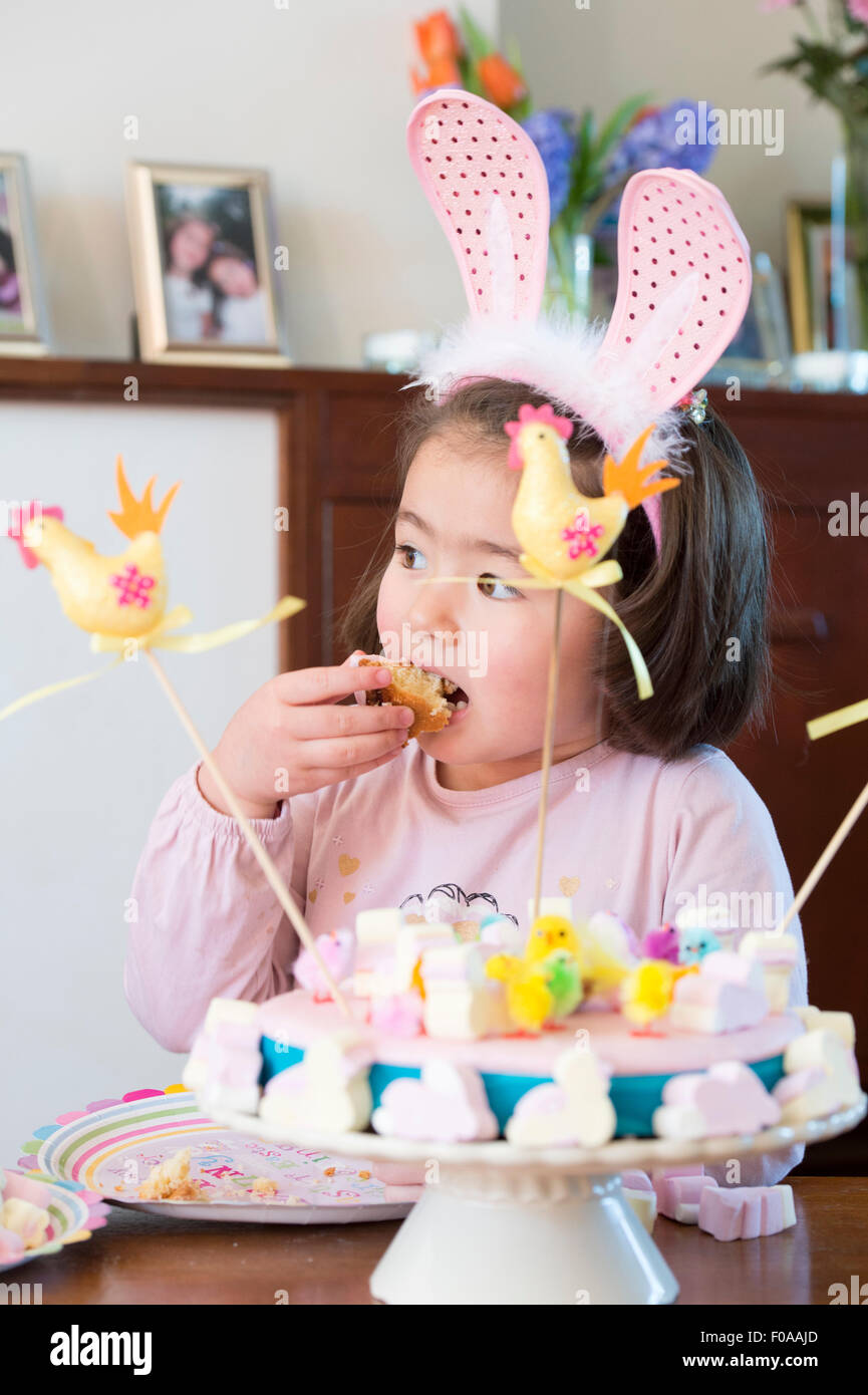 Young Girl wearing bunny ears, manger un gâteau Banque D'Images