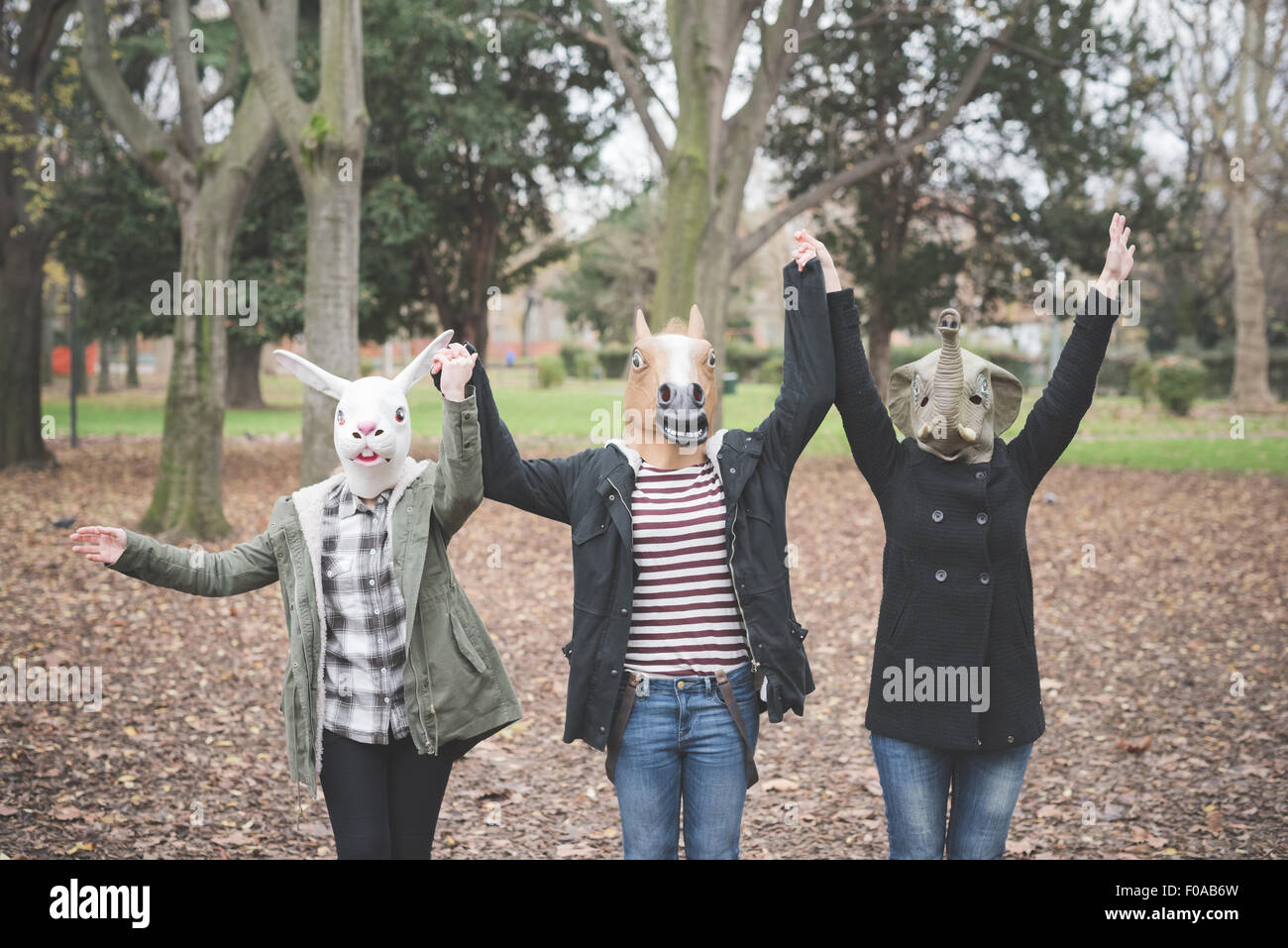 Trois sœurs portant des masques d'animaux dancing in park Banque D'Images