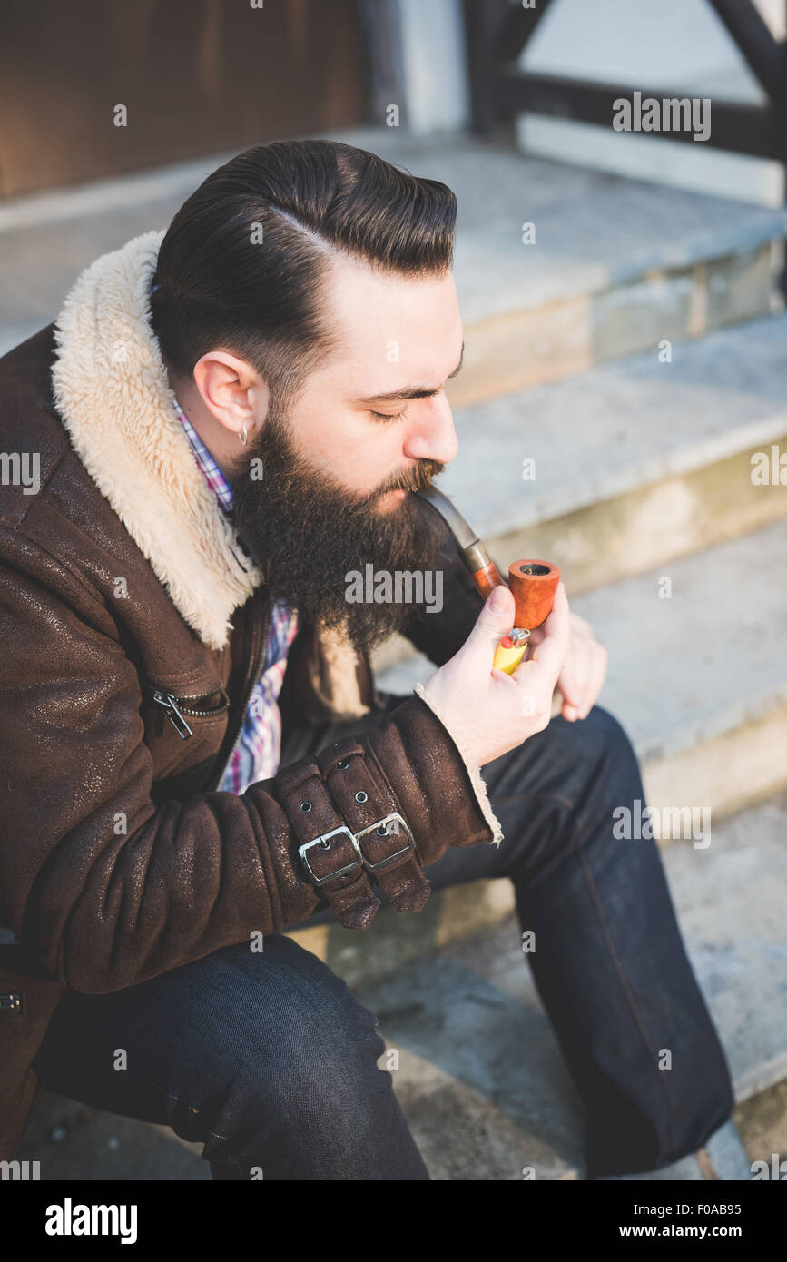 Jeune homme barbu pipe sur les mesures Banque D'Images