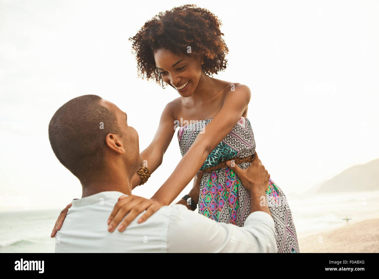 Mid adult man lifting up petite amie sur beach, Rio de Janeiro, Brésil Banque D'Images