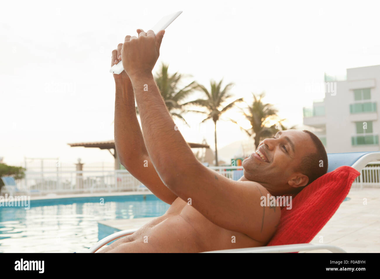 Mid adult man taking digital tablet à hotel selfies poolside, Rio de Janeiro, Brésil Banque D'Images