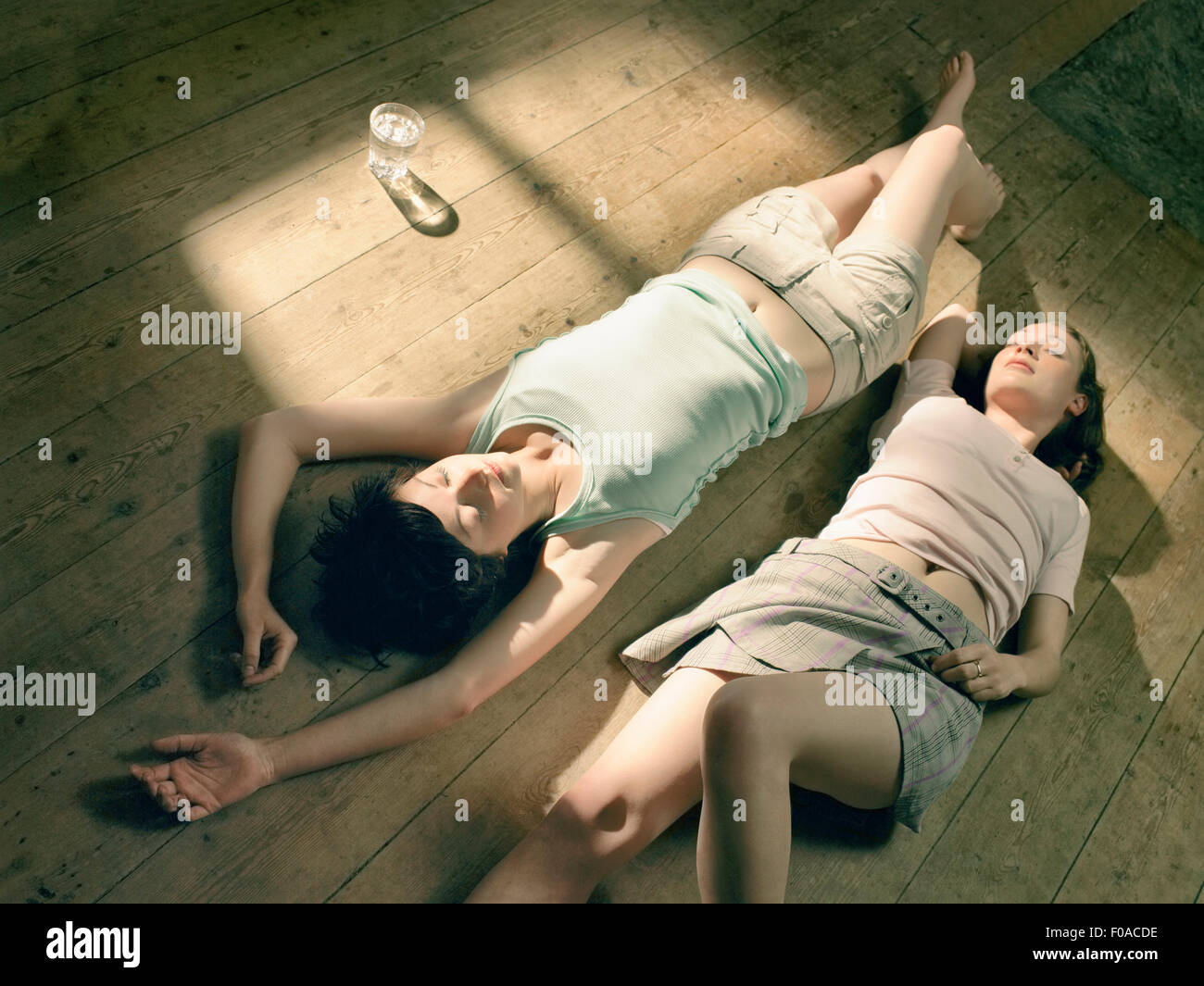 Deux jeunes femmes couché sur un plancher en bois dans la lumière du soleil Banque D'Images