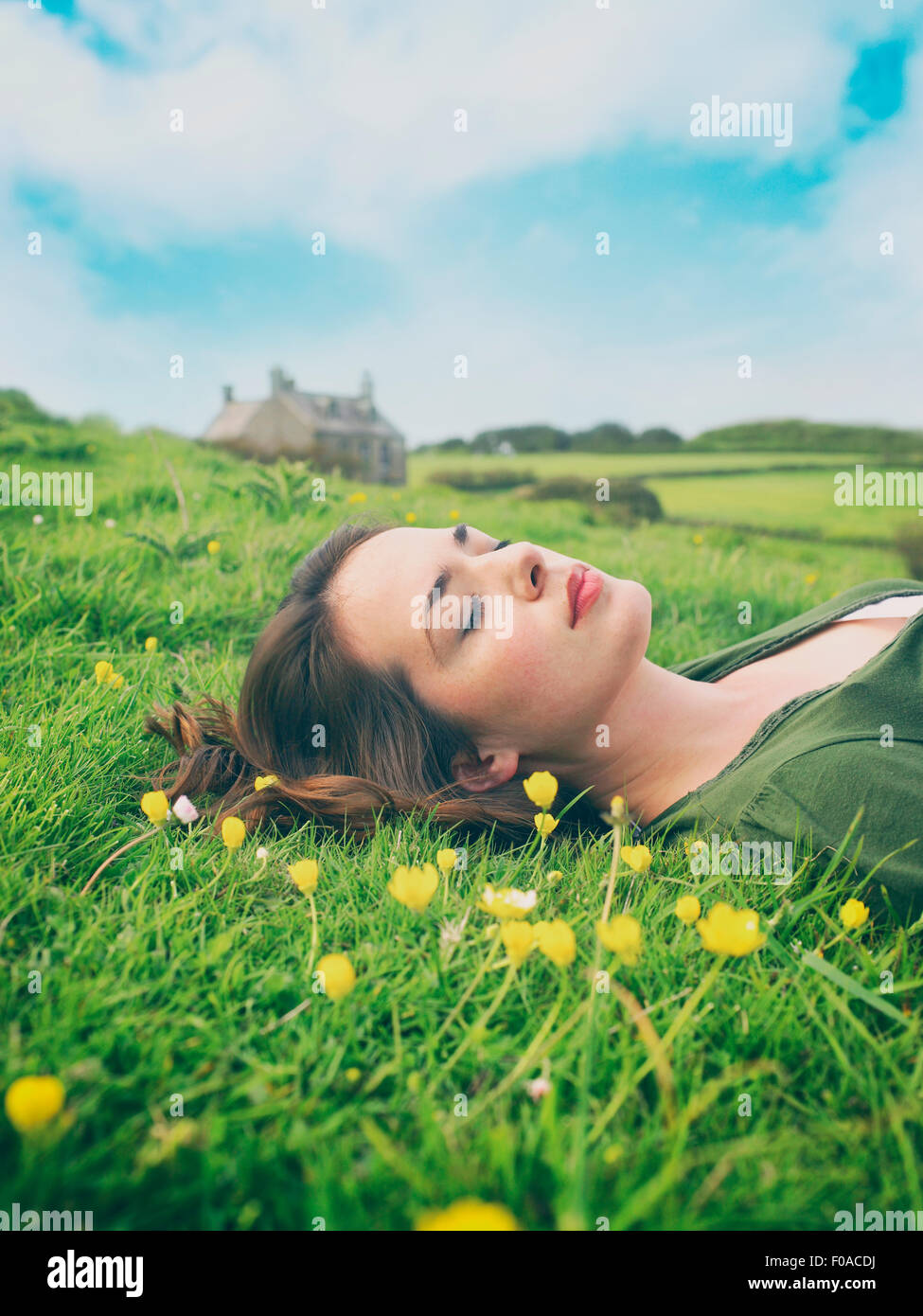 Les jeunes femmes avec les yeux fermé couché dans l'herbe de renoncule Banque D'Images