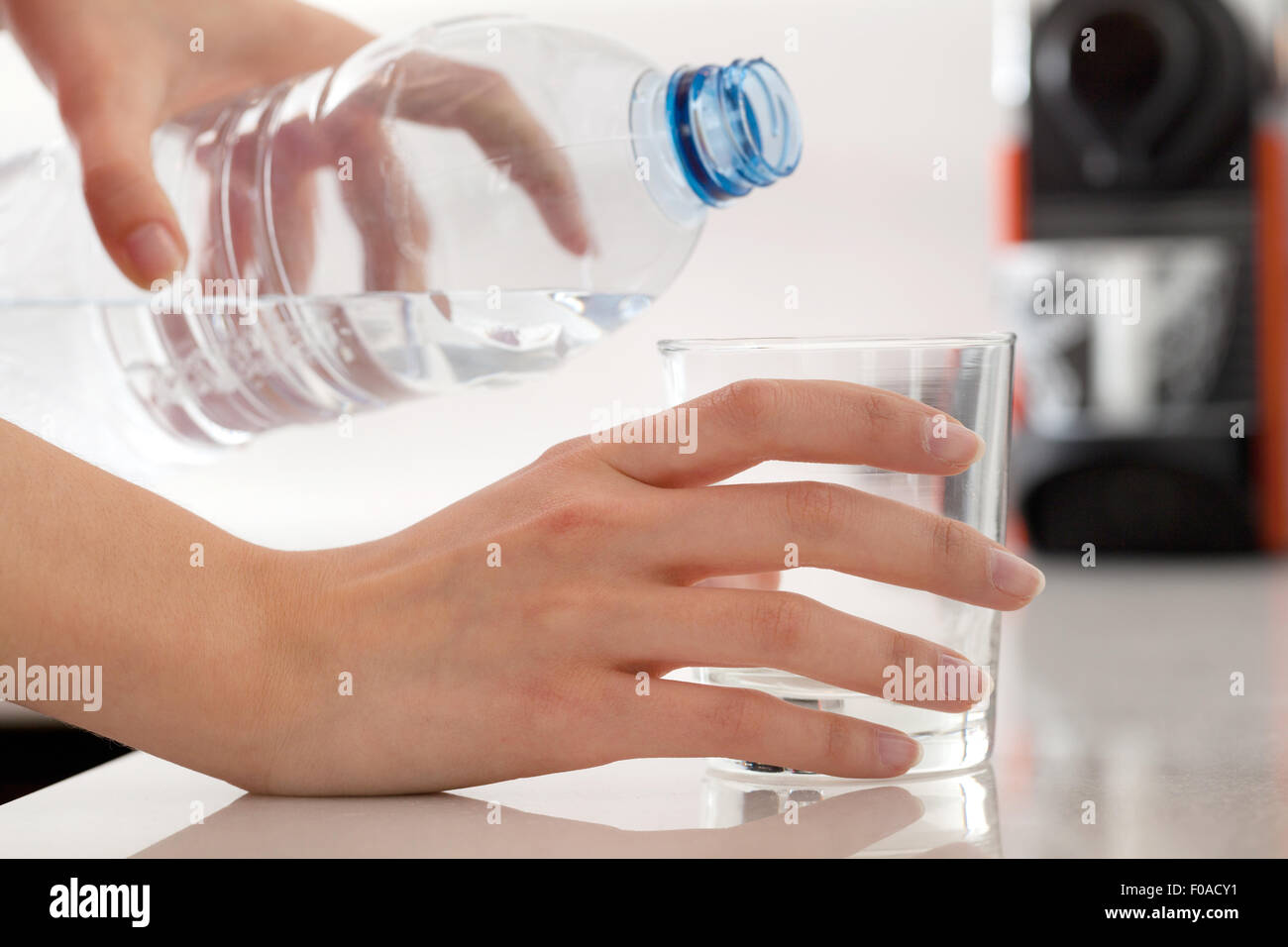 Verser de l'eau en bouteille des mains des femmes dans du verre Banque D'Images