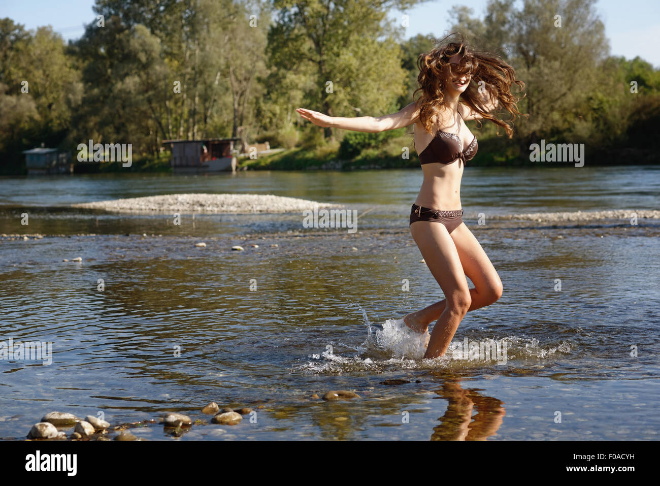 Jeune femme portant un bikini éclabousser et jouer dans la rivière Banque D'Images