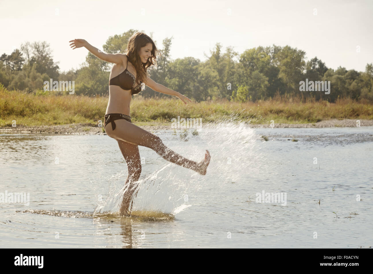 Jeune femme portant un bikini éclabousser et jouer dans la rivière Banque D'Images