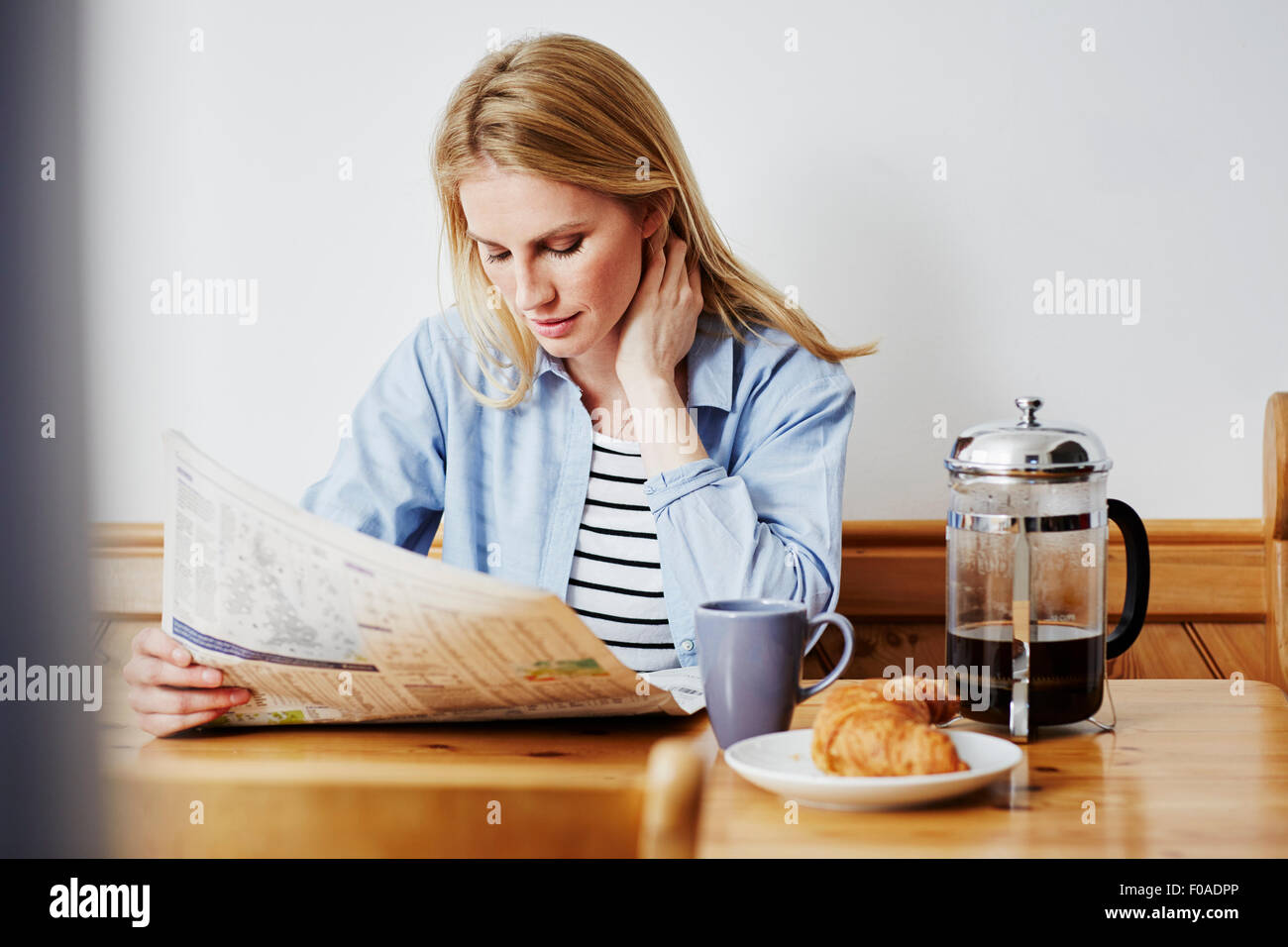 Mid adult woman reading newspaper Banque D'Images