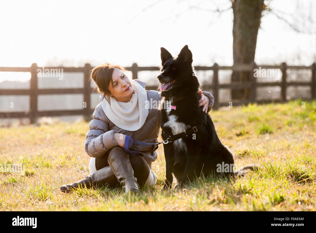 Mid adult woman sitting with her dog in field Banque D'Images