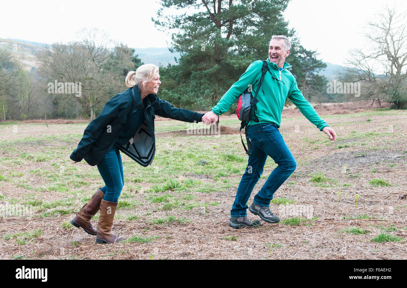 Randonnées couple holding hands and running in field Banque D'Images Randonnées couple holding hands and running in field Banque D'Images