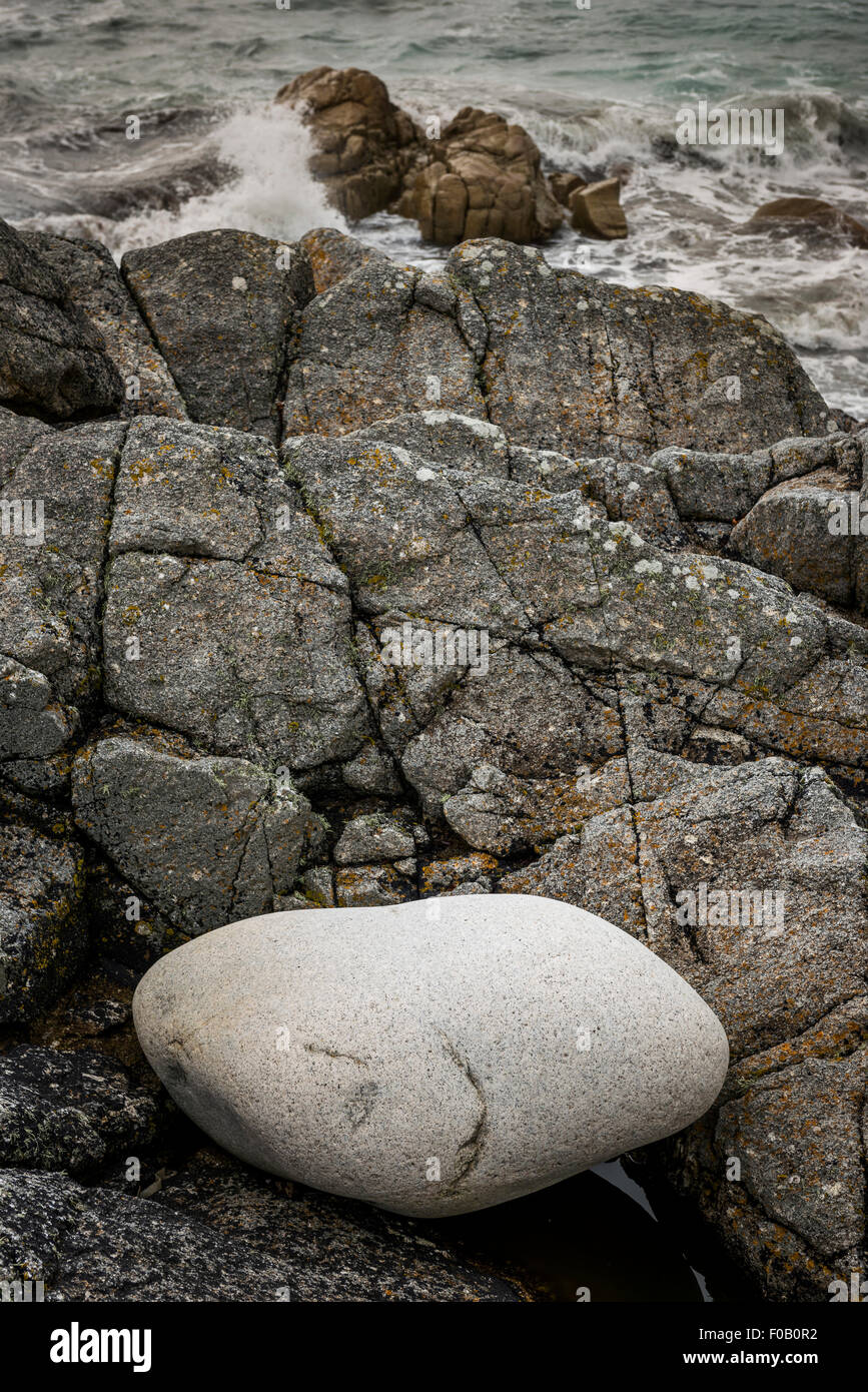 Un bon giant boulder atterri sur les rochers de granit par la mer à Porth Nanven, Penwith, Cornwall, UK Banque D'Images