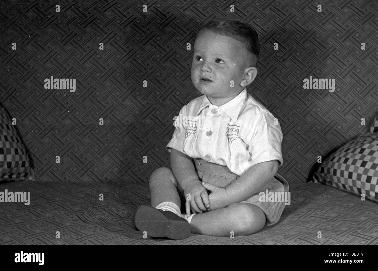 Un jeune garçon assis sur un canapé Banque D'Images