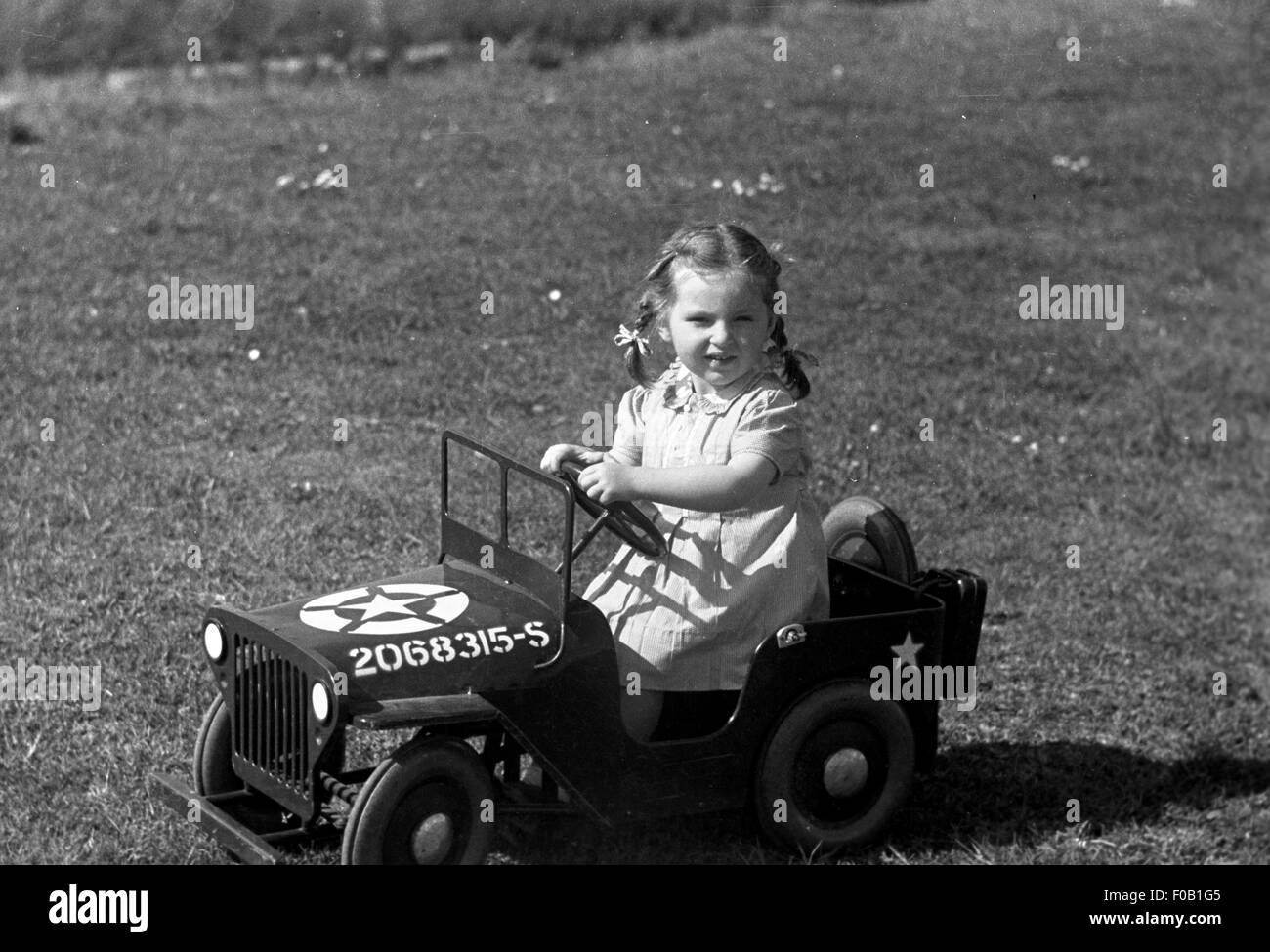 Portrait d'une jeune fille au volant d'une jeep américaine de jouets Banque D'Images