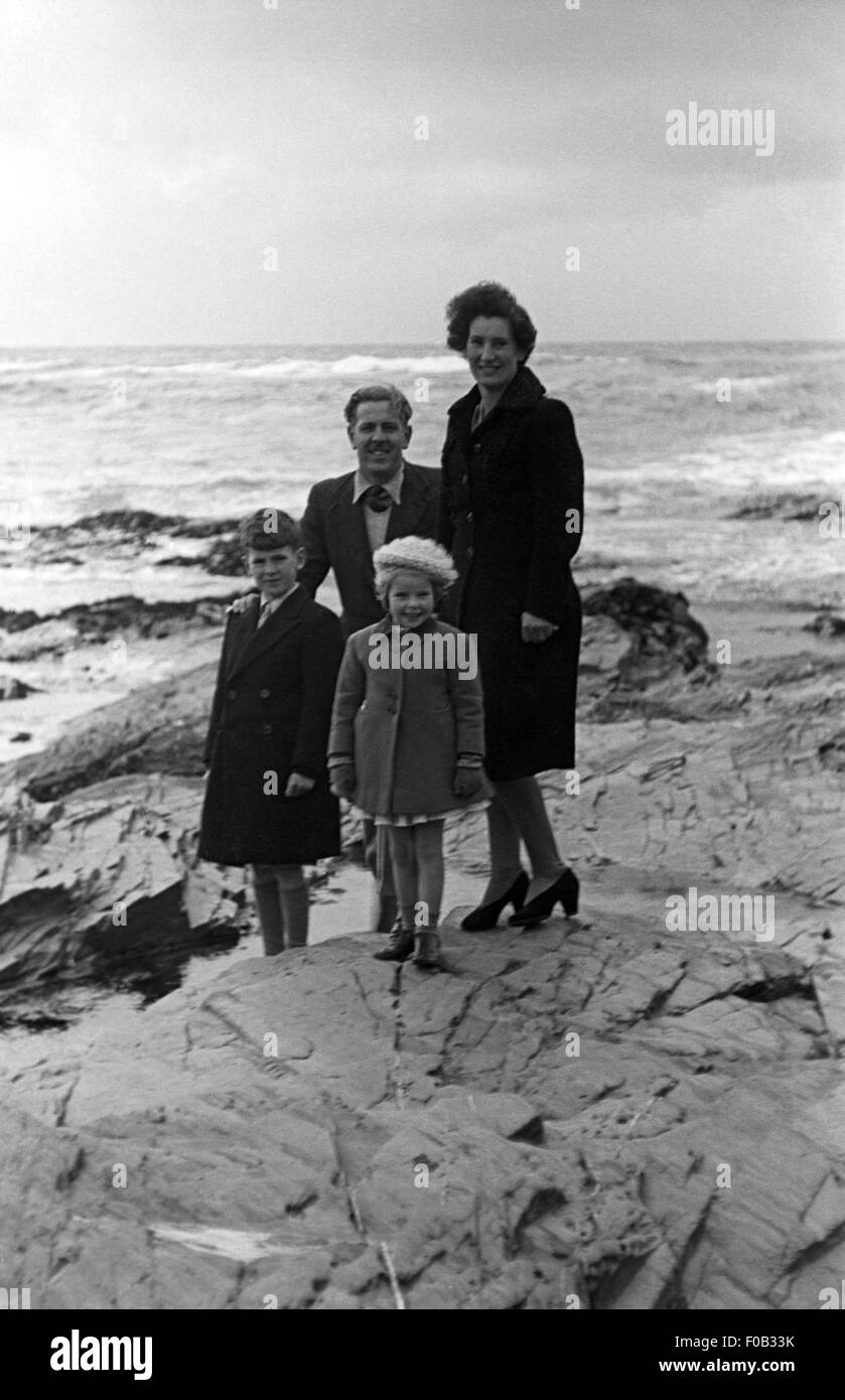 Une famille de quatre personnes debout sur des rochers au bord de la mer. Banque D'Images
