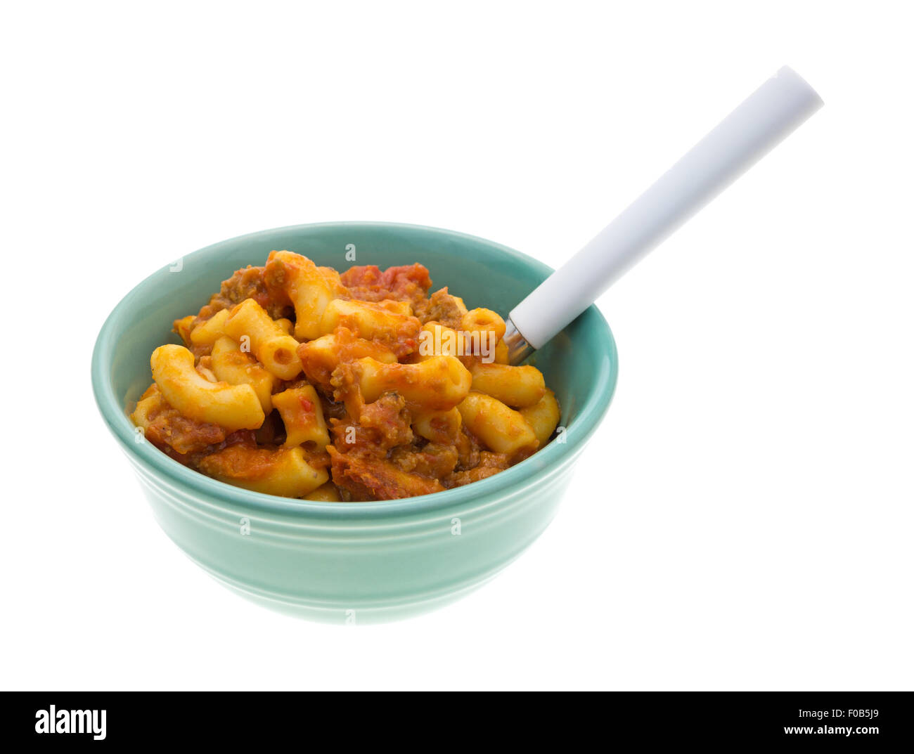 Une cuisson du boeuf et des macaronis repas dans un petit bol avec une cuillère sur un fond blanc. Banque D'Images