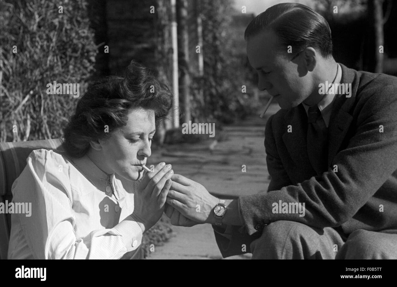 Un homme allumer une cigarette pour une femme. Banque D'Images