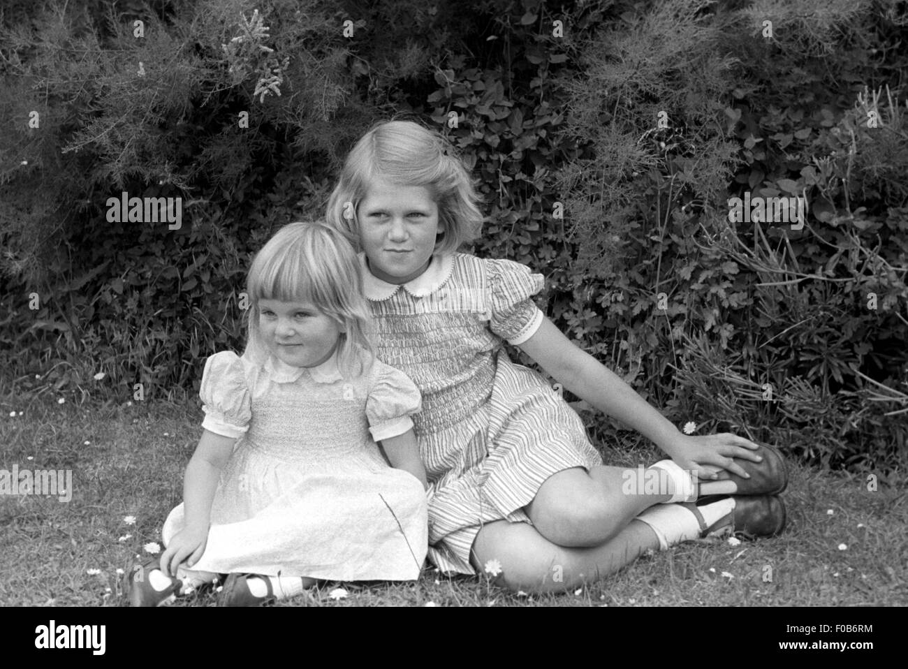 Deux jeunes filles en robes d'été assis sur l'herbe dans un jardin. Banque D'Images