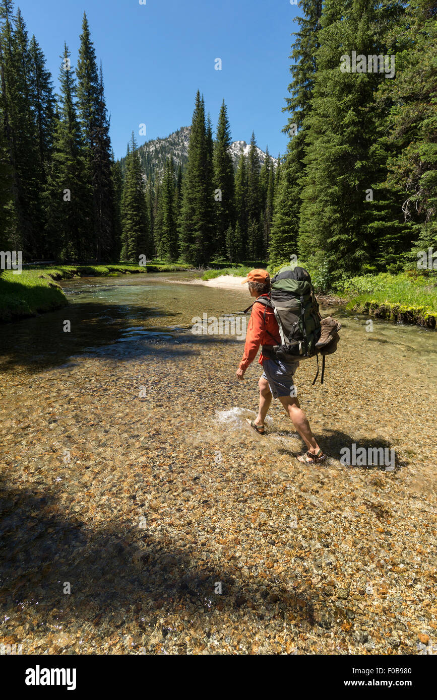 Backpacker traversant la fourche de l'ouest de la Rivière, montagnes Wallowa Lostine, Oregon. Banque D'Images