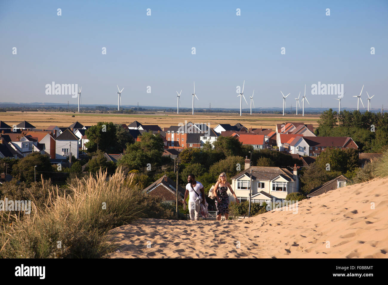 Les gens à marcher en direction de Camber Sands , avec le village de bombage (arrière-plan) près de Rye, East Sussex, England, UK Banque D'Images
