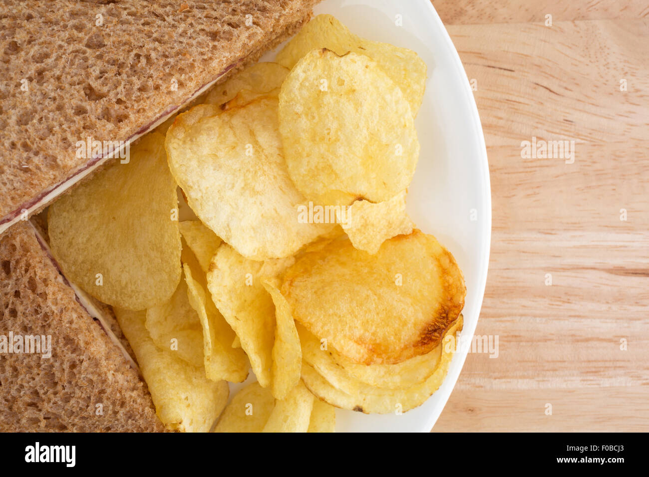 Haut de page fermer d'un sandwich de pain de blé rôti de bœuf avec du fromage blanc et la mayonnaise et croustilles de pommes de terre sur une plaque blanche au sommet d'un w Banque D'Images