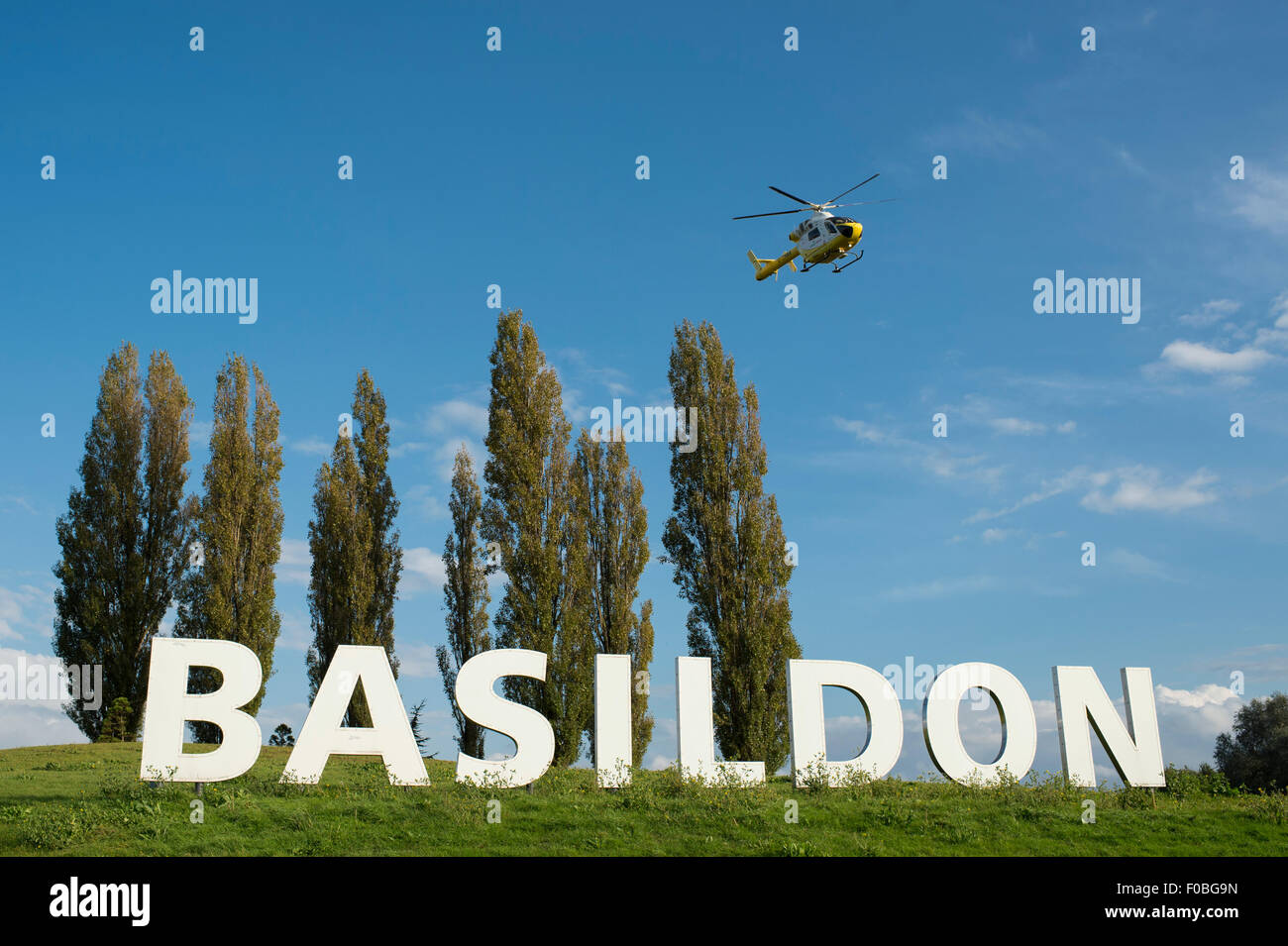 La désormais célèbre signe de Basildon à l'entrée de la ville d'Essex avec l'EISU et Essex Air Ambulance L'atterrissage à côté. Banque D'Images