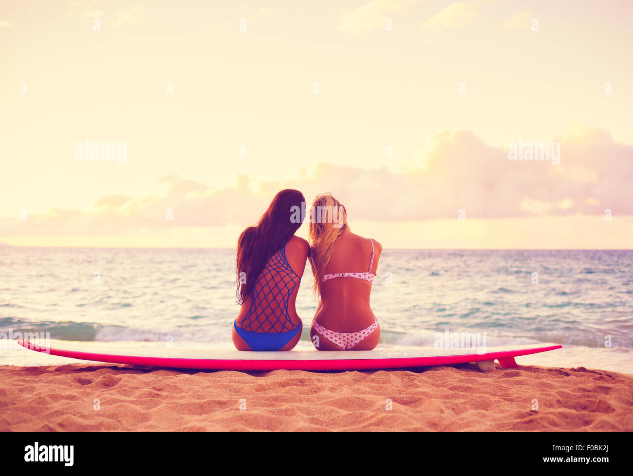 Surfer Girls sur la plage au coucher du soleil. Style de vie en plein air d'été. Meilleurs amis flâner sur la plage. Banque D'Images
