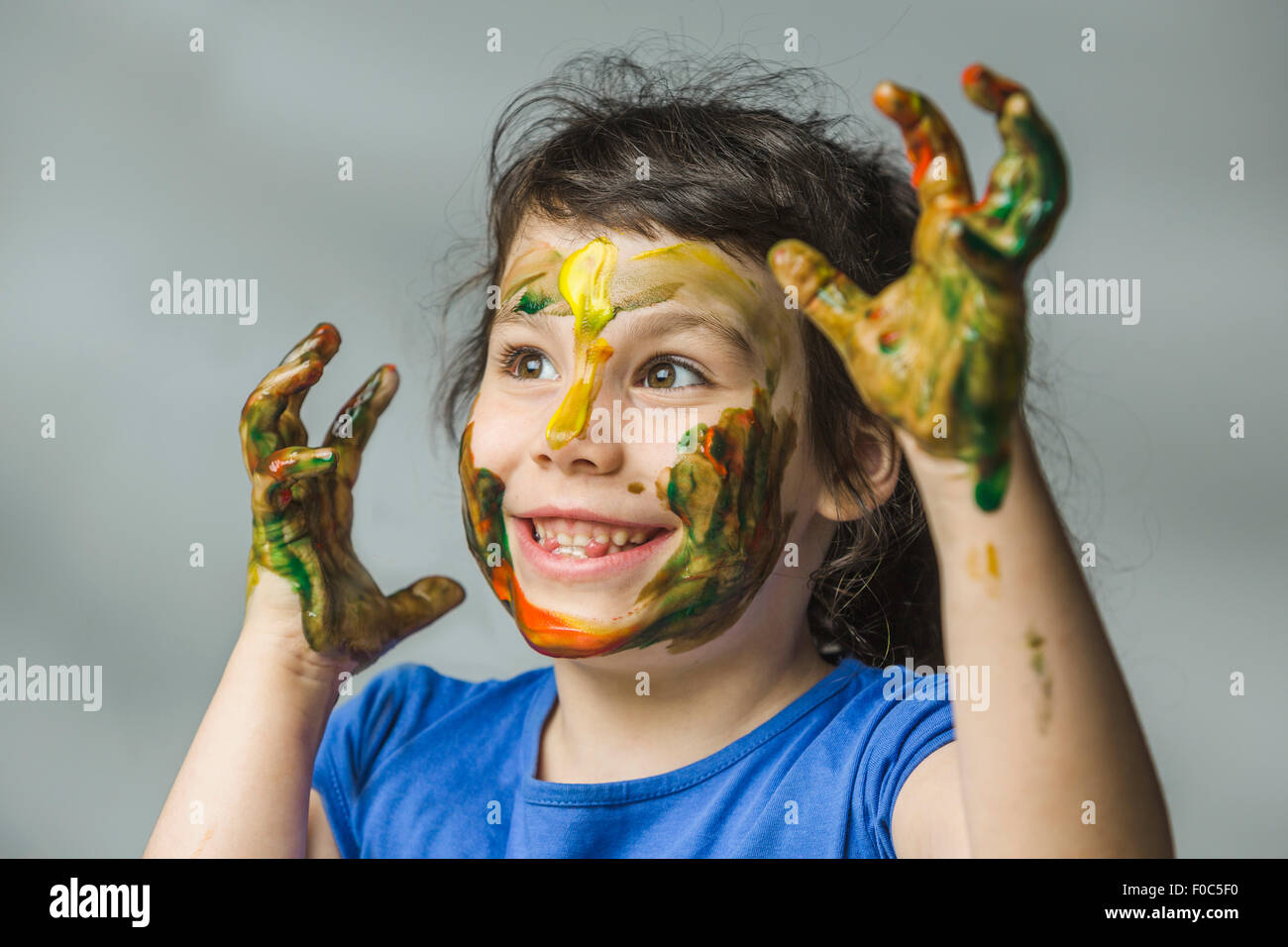 Smiling girl avec le visage et les mains peints sur fond gris Banque D'Images