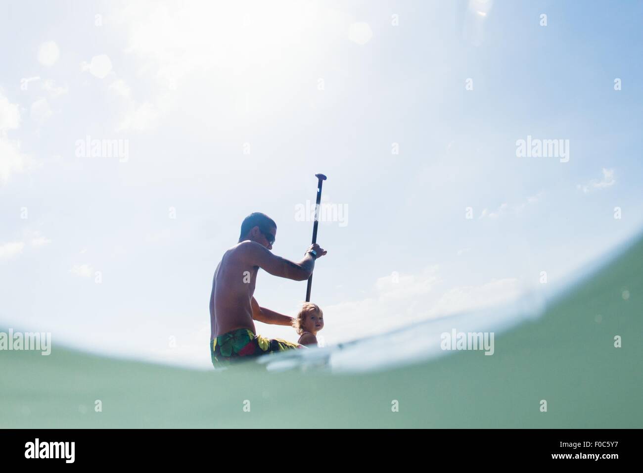 Low angle view of young man and toddler fille paddleboarding Banque D'Images