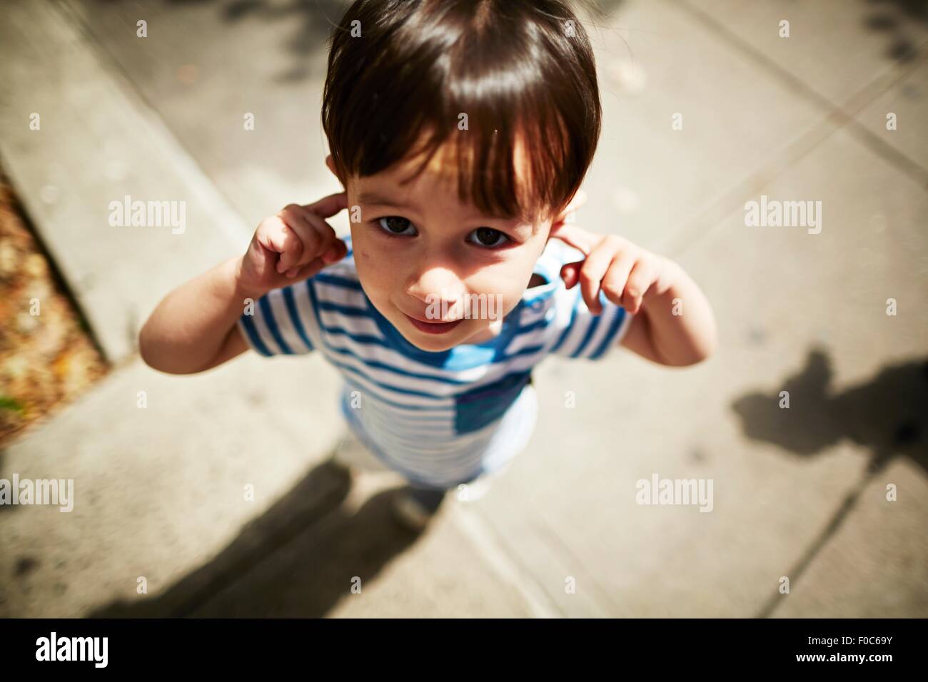 Portrait de jeune garçon en mettant ses doigts dans ses oreilles sur street Banque D'Images