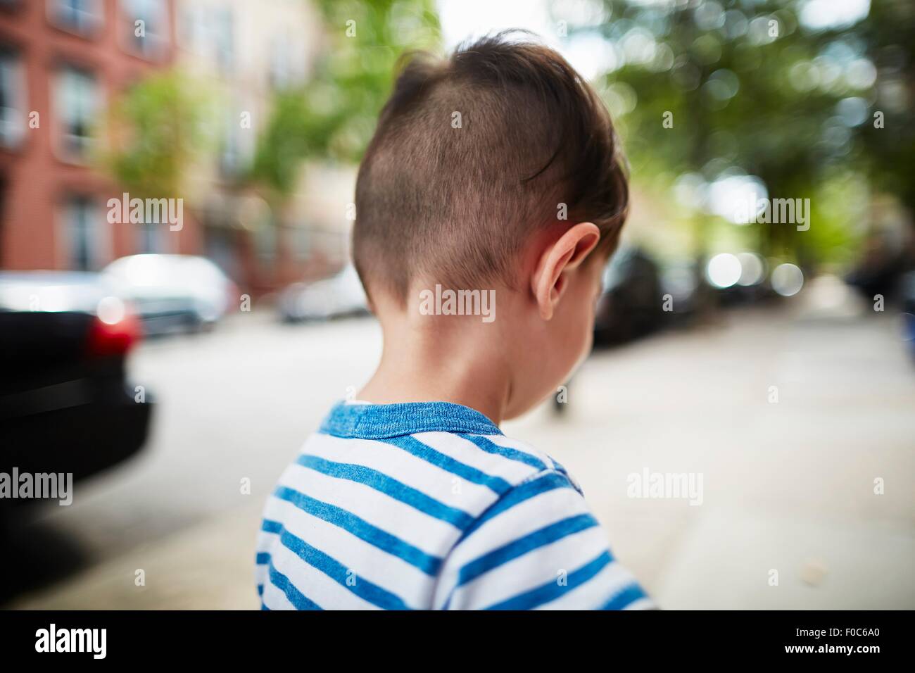 Vue arrière de boy walking down street Banque D'Images