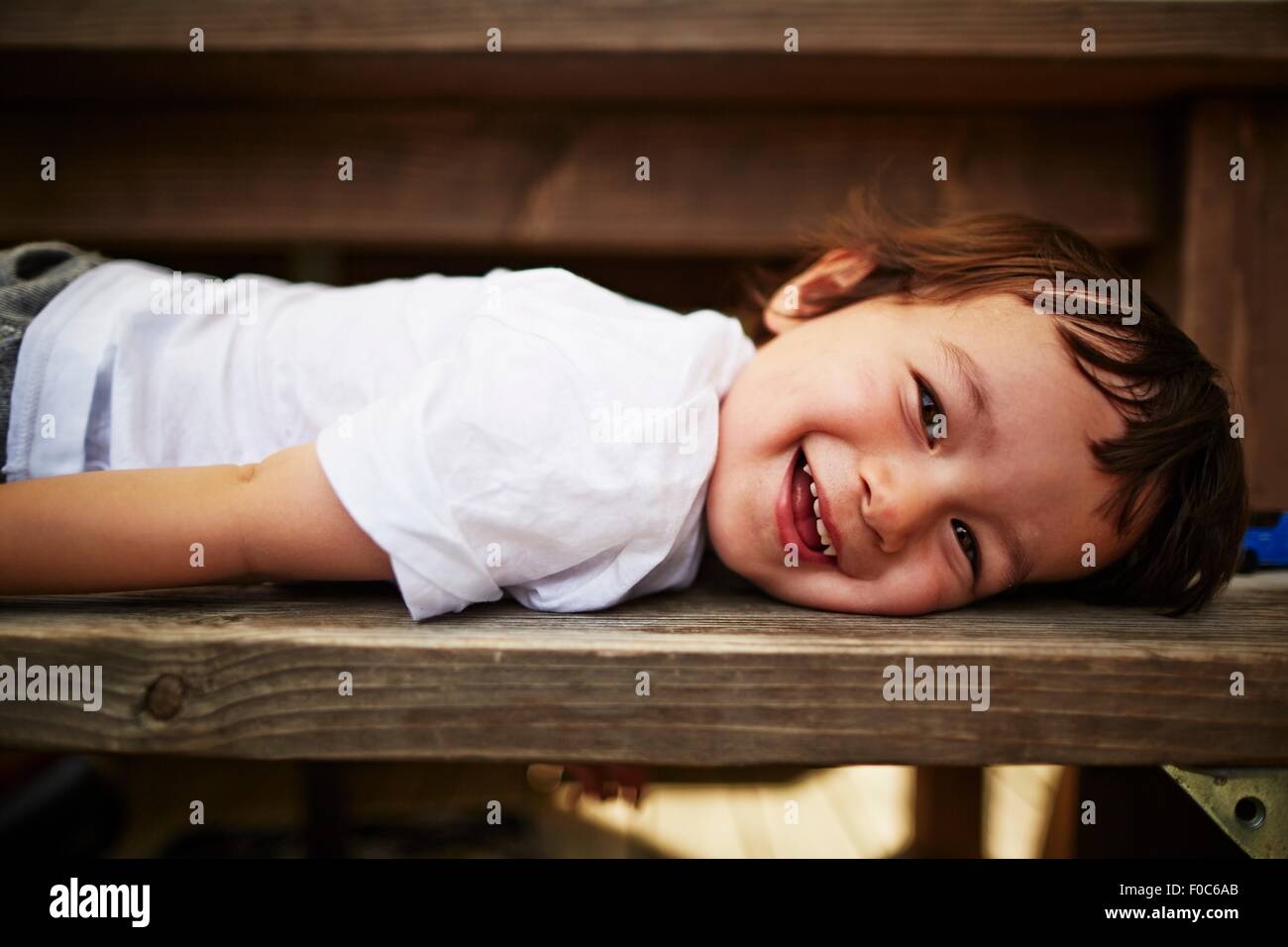 Portrait of smiling boy laying on bench Banque D'Images