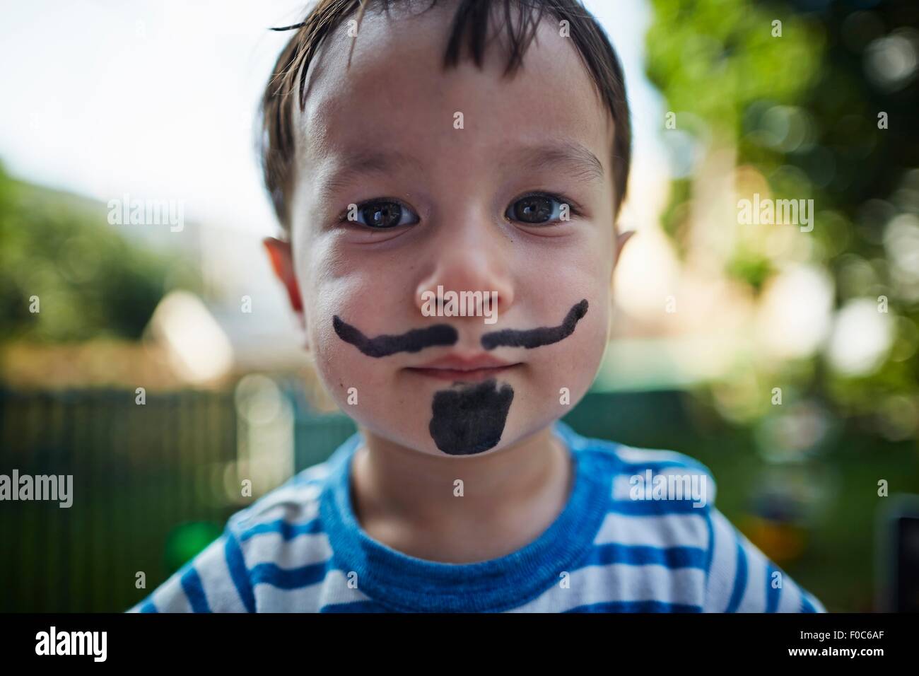 Close up portrait of boy looking at camera portant barbe et moustache costume face paint Banque D'Images
