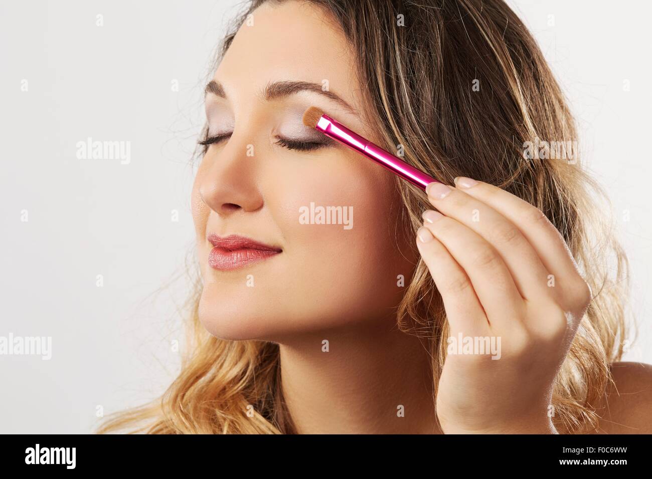Young woman applying eyeshadow Banque D'Images