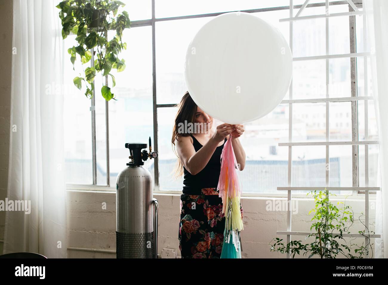 Jeune femme attachant bunting à balloon in design studio Banque D'Images