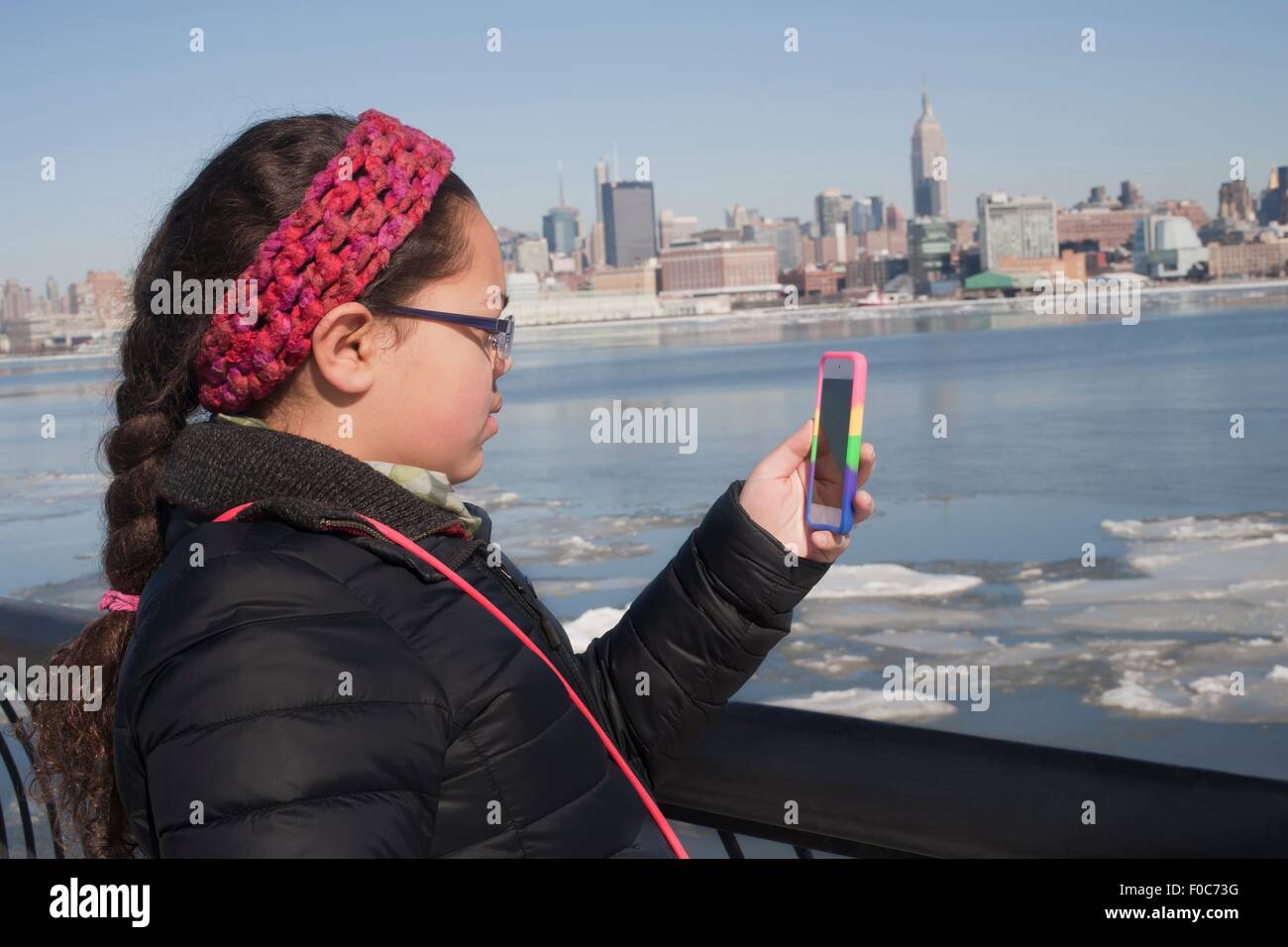 Young Girl taking photograph of skyline en utilisant smartphone, New York, NY, USA Banque D'Images