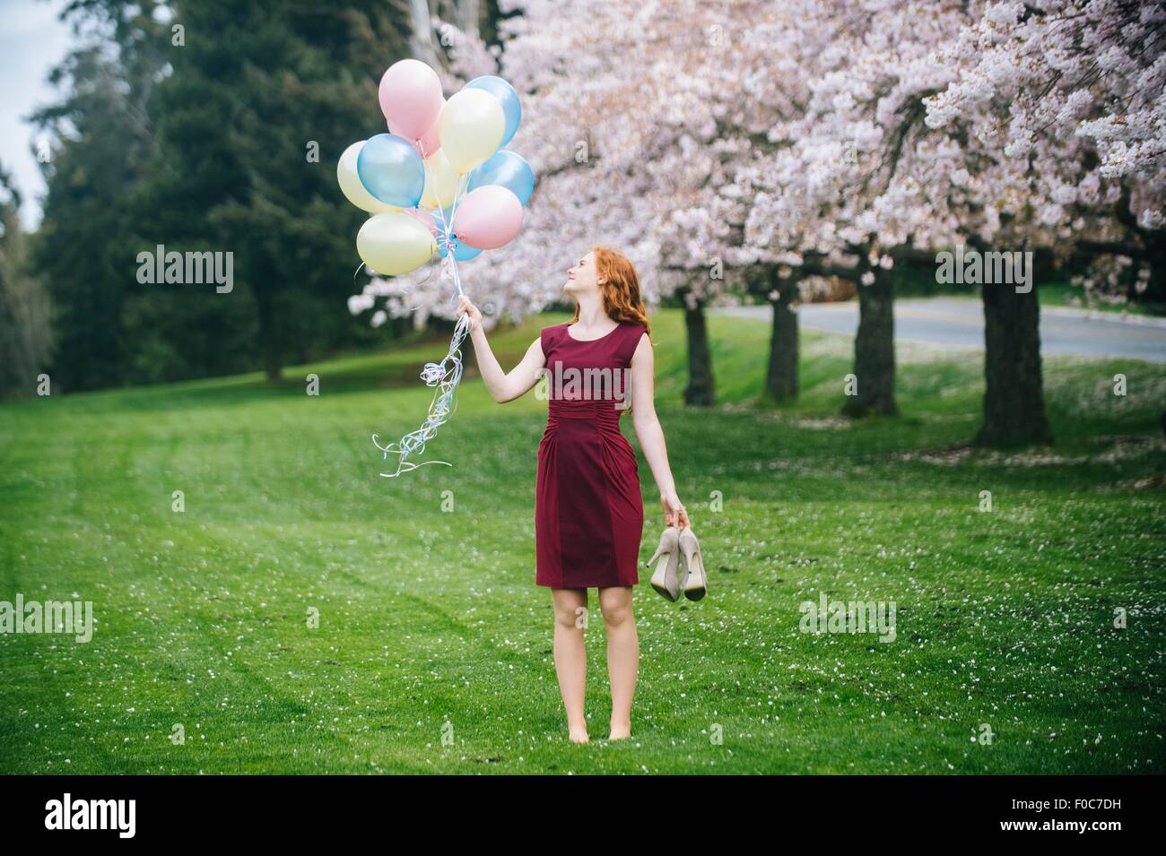 Young woman holding bunch of balloons dans spring park Banque D'Images