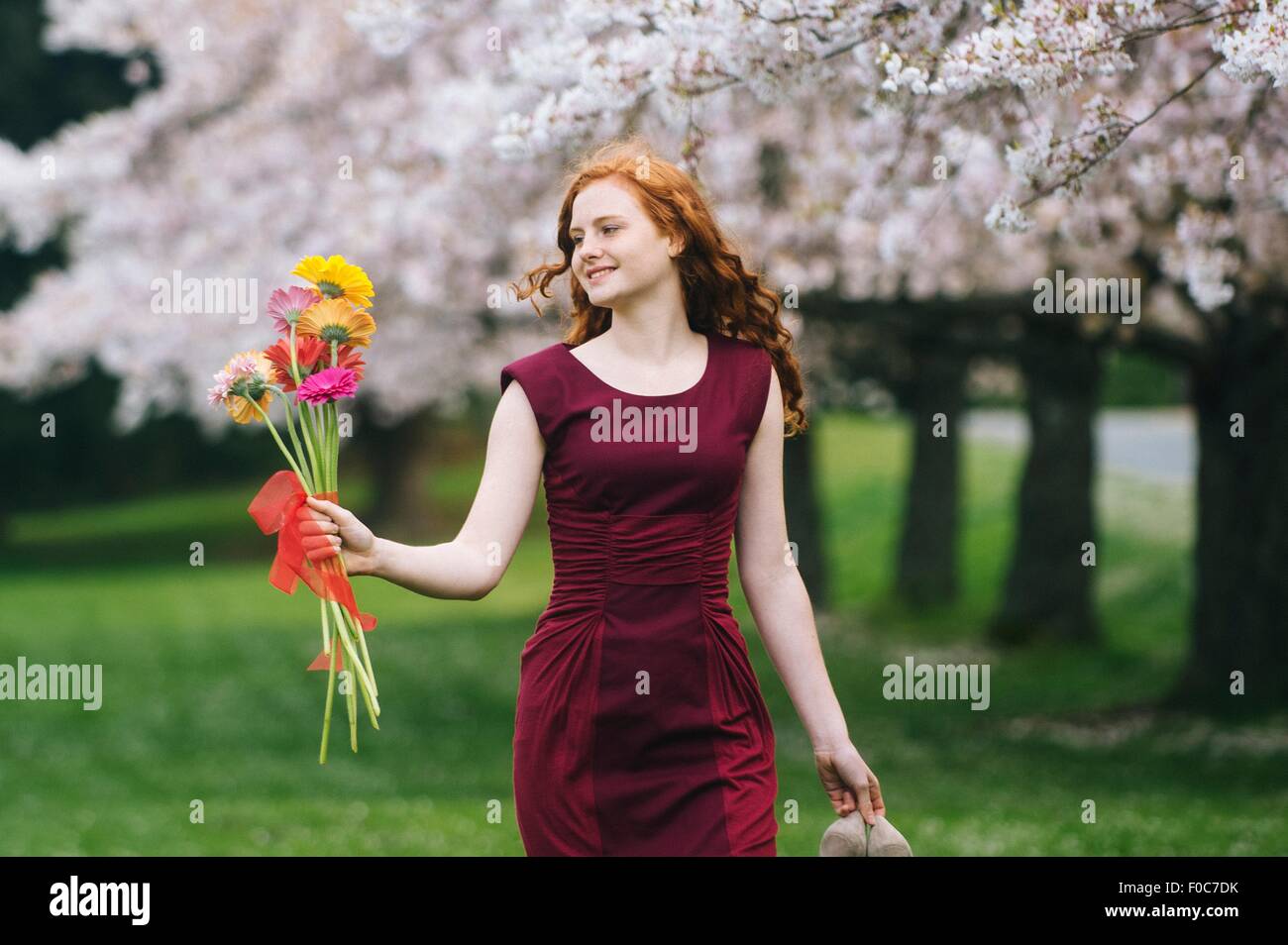 Young woman holding bunch of flowers in spring park Banque D'Images