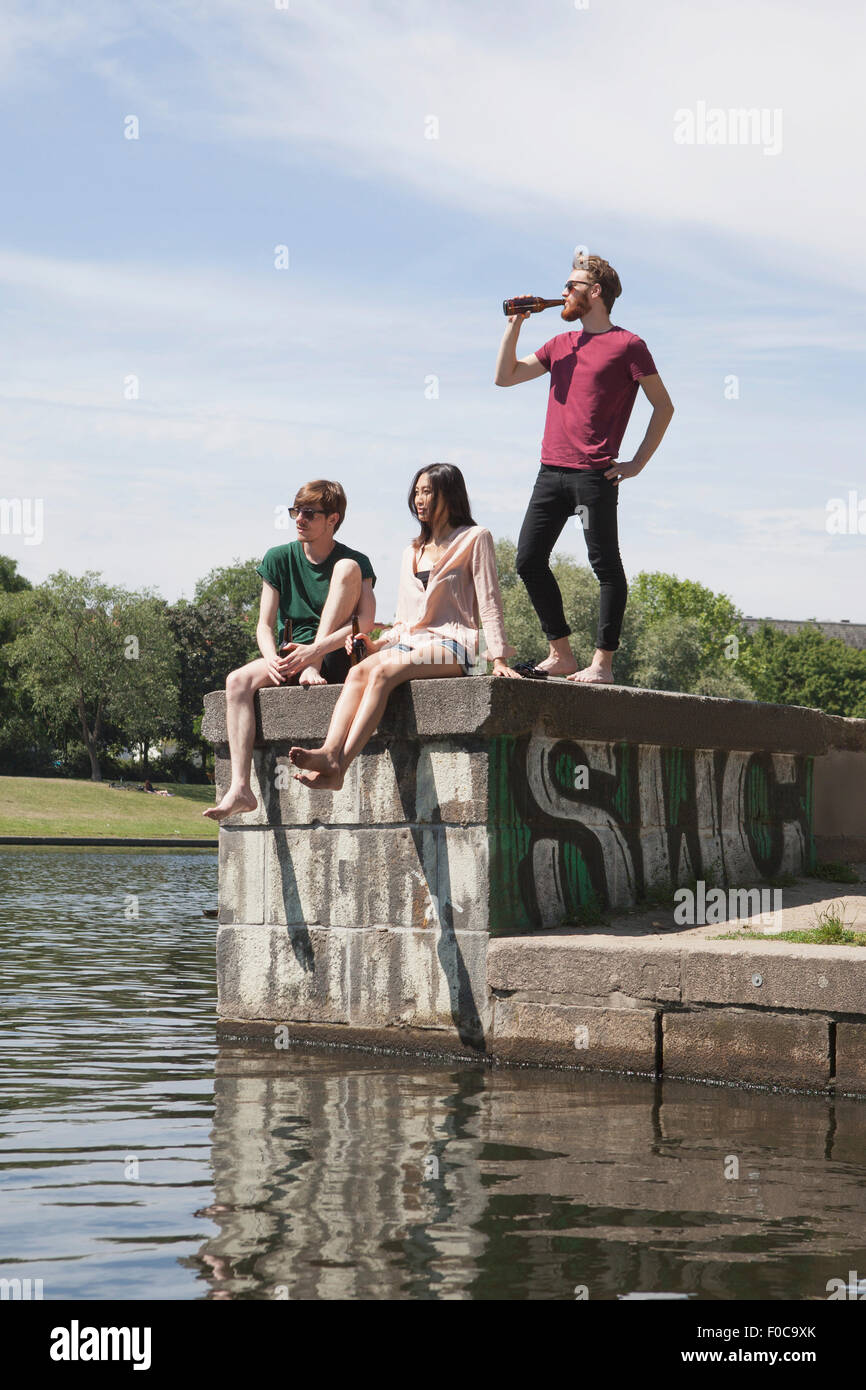 Multi-ethnic friends ayant la bière sur le mur de retenue par canal Banque D'Images