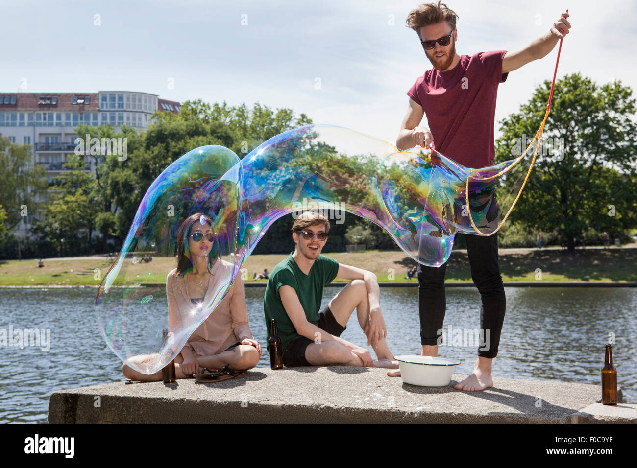 Happy friends enjoying avec grosse bulle sur mur de retenue par canal à park Banque D'Images