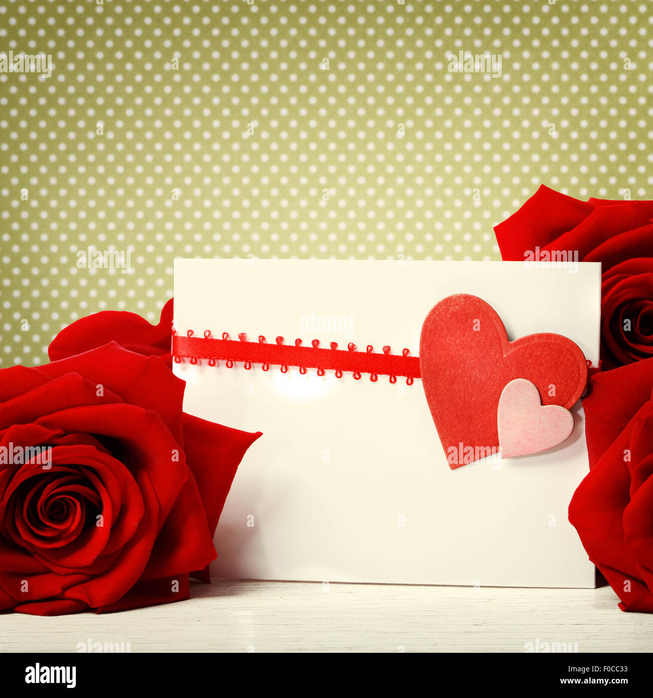Carte de souhaits coeurs avec de belles roses rouges sur fond vert petits pois Banque D'Images