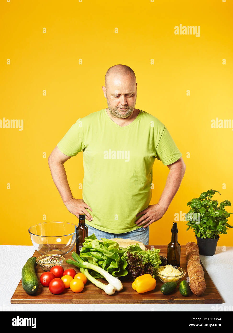 Salade fraîche ingrédients sur la table, homme d'âge moyen - copie l'espace et le fond jaune Banque D'Images