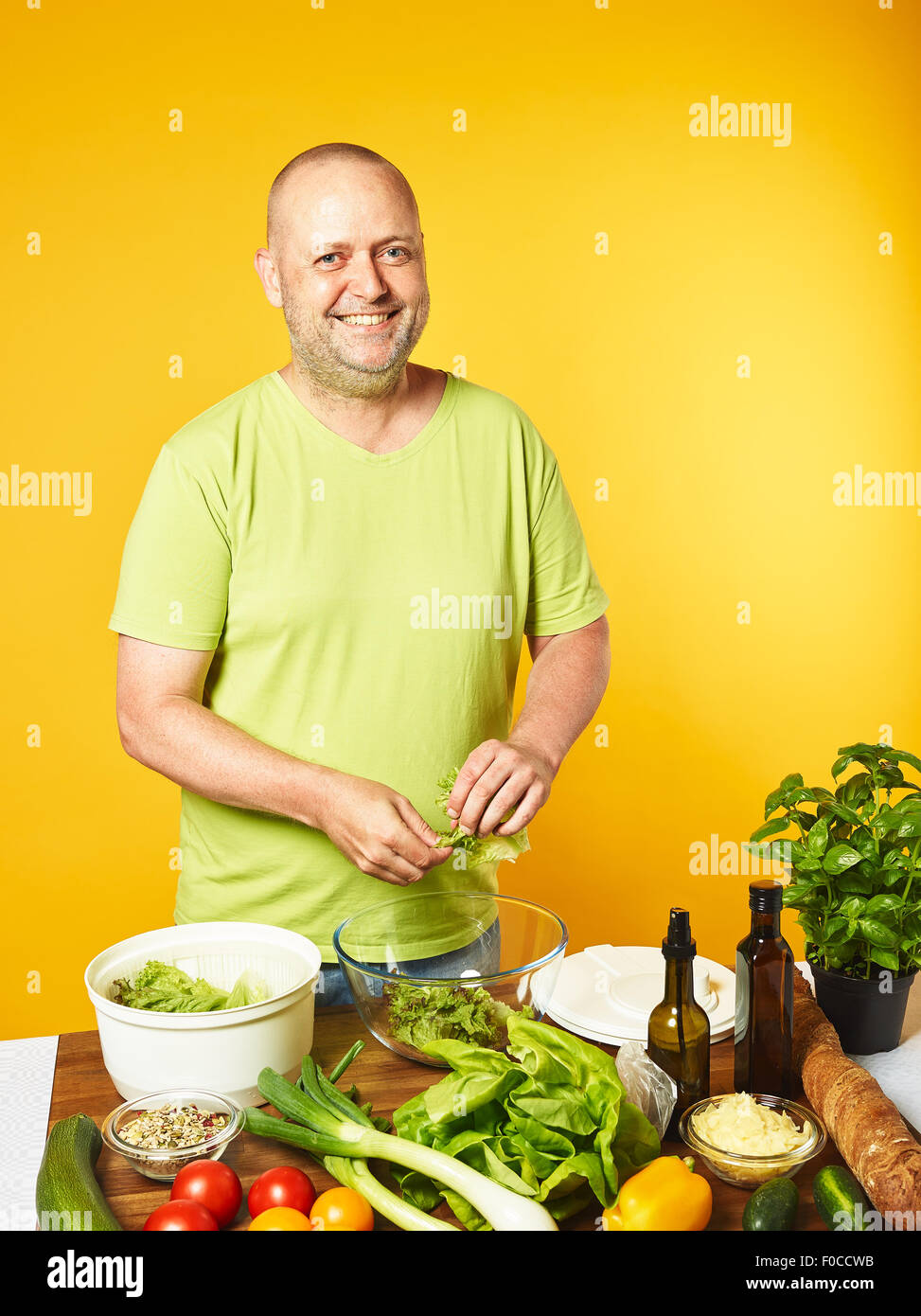 Salade fraîche ingrédients sur la table, homme d'âge moyen et salade Salade cook utilisé spin cheveux - copie espace et fond jaune Banque D'Images