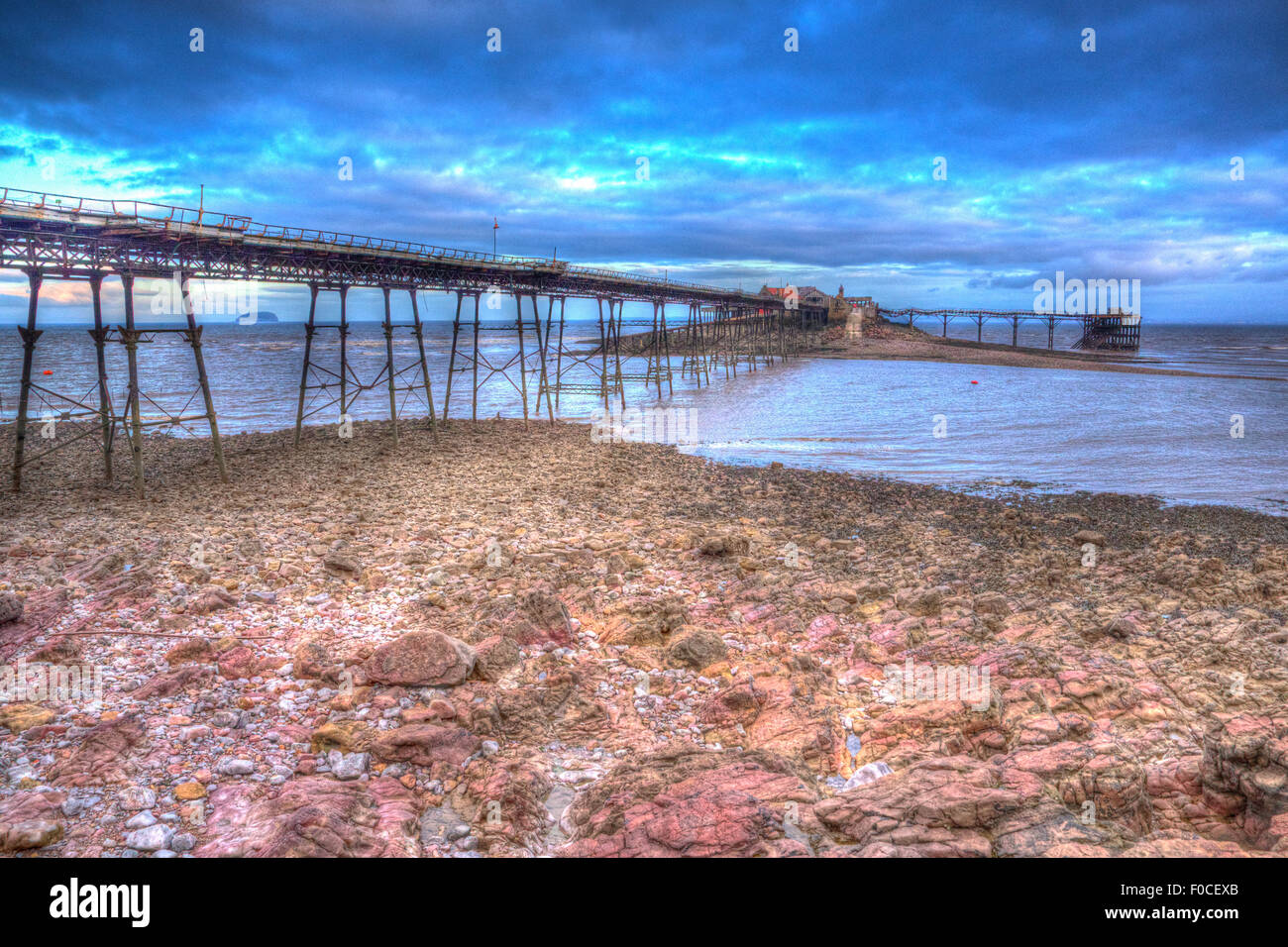 Birnbeck Pier Weston-super-Mare dans le Somerset en Angleterre HDR colorés comme la peinture rouge avec des rochers en premier plan Banque D'Images